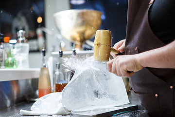 Image showing Bartender mannually crushed ice with wooden hammer and metal knife.