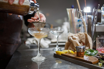 Image showing Bartender coocks cocktail behind a bar counter