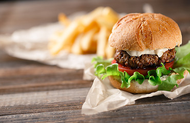 Image showing Homemade burger with french fries on wooden table