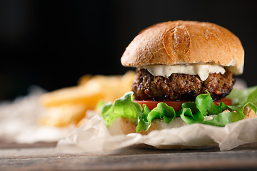 Image showing Homemade burger with french fries on wooden table