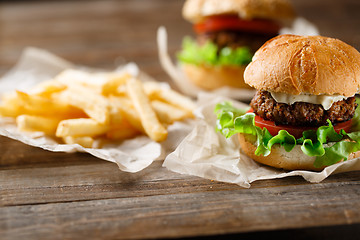 Image showing Homemade tasty burger and french fries on wooden table