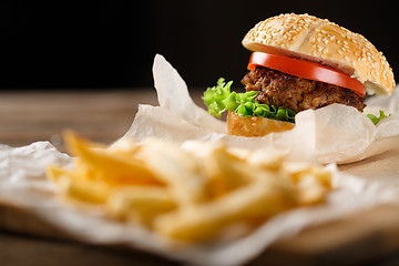 Image showing Homemade hamburgers and french fries on wooden table