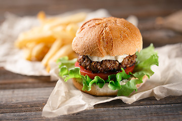 Image showing Homemade burger with french fries on wooden table
