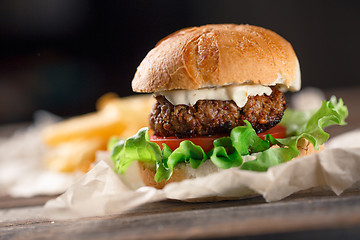 Image showing Homemade burger with french fries on wooden table