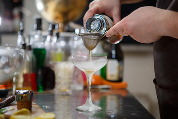 Image showing Bartender coocks cocktail behind a bar counter