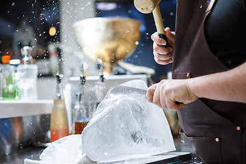 Image showing Bartender mannually crushed ice with wooden hammer and metal knife.