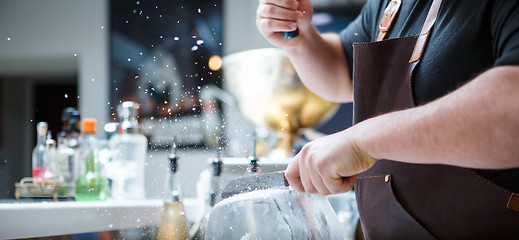 Image showing Bartender breaks ice with wooden hammer