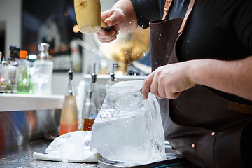 Image showing Bartender mannually crushed ice with wooden hammer and metal knife.