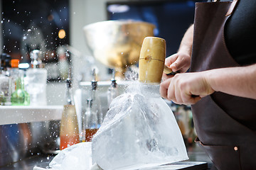 Image showing Bartender mannually crushed ice with wooden hammer and metal knife.