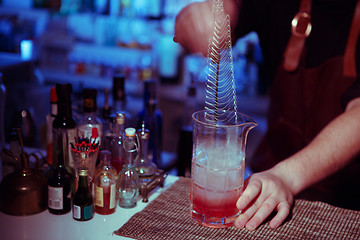 Image showing Bartender nixed cocktail in glass cup.