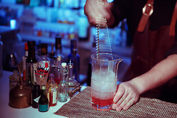 Image showing Bartender nixed cocktail in glass cup.