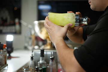 Image showing Bartender at work preparing cocktails. Shaking cocktail shaker. 