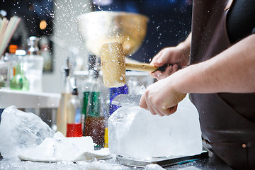 Image showing Bartender mannually crushed ice with wooden hammer and metal knife.