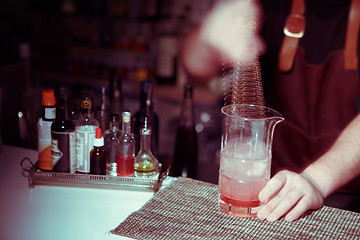 Image showing Bartender nixed cocktail in glass cup.