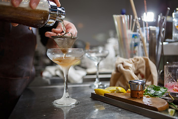 Image showing Bartender coocks cocktail behind a bar counter