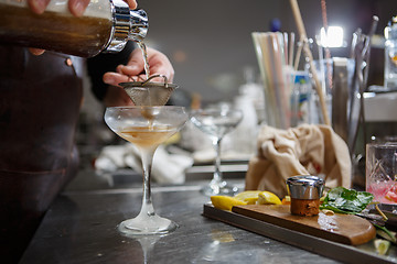 Image showing Bartender coocks cocktail behind a bar counter