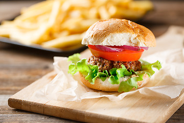 Image showing Homemade burger with french fries on wooden table