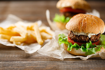 Image showing Homemade tasty burger and french fries on wooden table