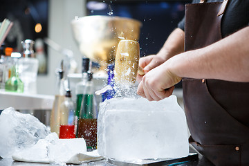 Image showing Bartender mannually crushed ice with wooden hammer and metal knife.