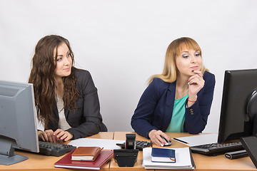 Image showing Office worker looking with distaste at the colleague sitting next to staring at a computer monitor