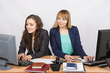 Image showing Office worker on the sly looks at the monitor unsuspecting colleagues