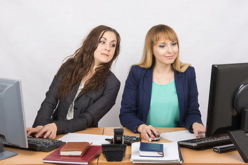 Image showing Office worker on the sly looks at the monitor colleague sitting next to a computer