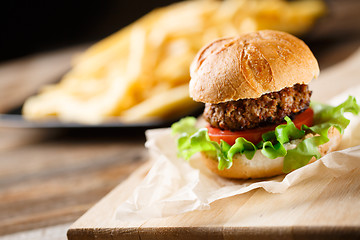 Image showing Homemade burger with french fries on wooden table