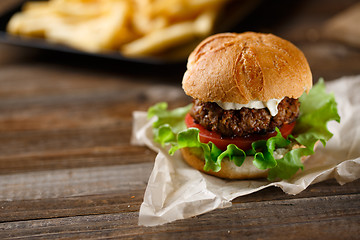 Image showing Homemade burger with french fries on wooden table