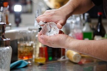 Image showing Bartender pours alcoholic drink into small glasses with flames