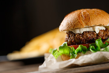 Image showing Homemade burger with french fries on wooden table