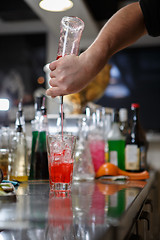 Image showing Bartender coocks cocktail behind a bar counter