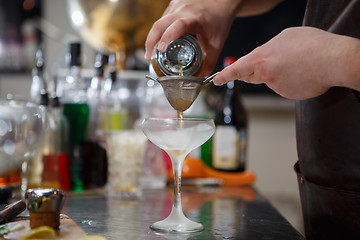 Image showing Bartender coocks cocktail behind a bar counter