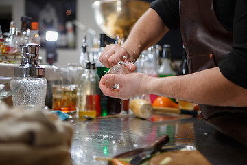 Image showing Bartender pours alcoholic drink into small glasses with flames