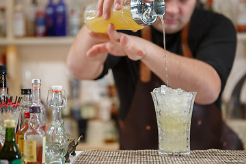 Image showing Bartender pouring cocktail into glass at the bar