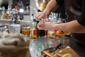 Image showing Bartender pours alcoholic drink into small glasses with flames