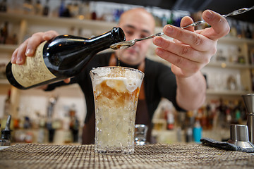 Image showing Bartender pouring cocktail into glass at the bar