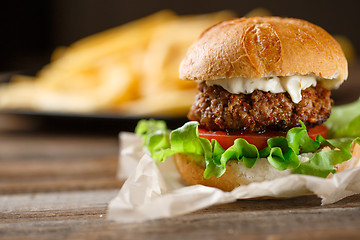 Image showing Homemade burger with french fries on wooden table