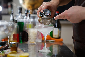 Image showing Bartender coocks cocktail behind a bar counter