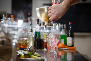 Image showing Bartender coocks cocktail behind a bar counter