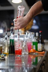 Image showing Bartender coocks cocktail behind a bar counter