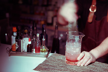 Image showing Bartender nixed cocktail in glass cup.