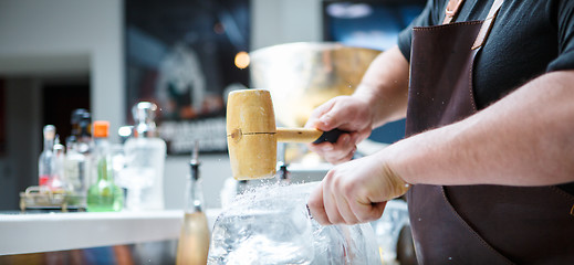 Image showing Bartender mannually crushed ice with wooden hammer and metal knife.