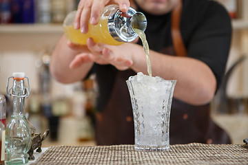 Image showing Bartender pouring cocktail into glass at the bar