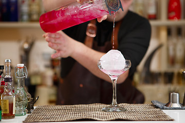 Image showing barman pouring a pink cocktail drink 