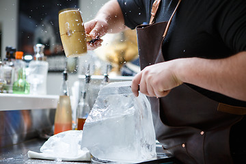 Image showing Bartender mannually crushed ice with wooden hammer and metal knife.