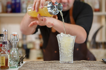 Image showing Bartender pouring cocktail into glass at the bar