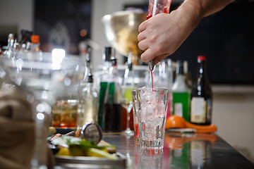 Image showing Bartender coocks cocktail behind a bar counter