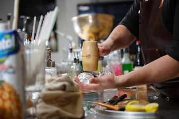 Image showing Bartender pours alcoholic drink into small glasses with flames