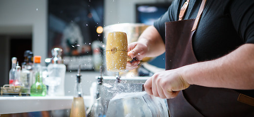 Image showing Bartender breaks ice with wooden hammer