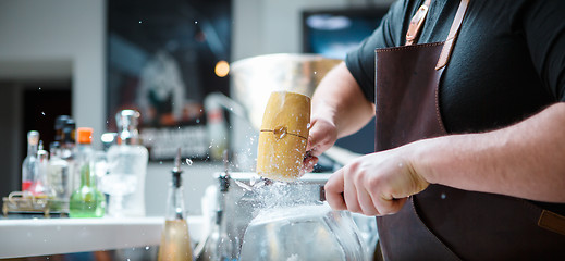 Image showing Bartender breaks ice with wooden hammer